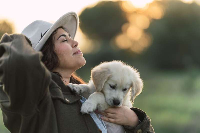 Frau mit Golden Retriever Welpen auf dem Arm